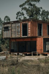 A rustique structure de maison conteneur située dans un environnement boisé naturel.