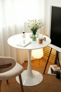 A serene and elegantly arranged table setup with daisies, books, and decor in a stylish room. Configuration élégante et sereine d'une table avec des marguerites, des livres et de la décoration dans une pièce stylée.