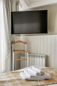 Chambre d'hôtel cosy avec une télévision et des serviettes fraîchement pliées sur le lit.
