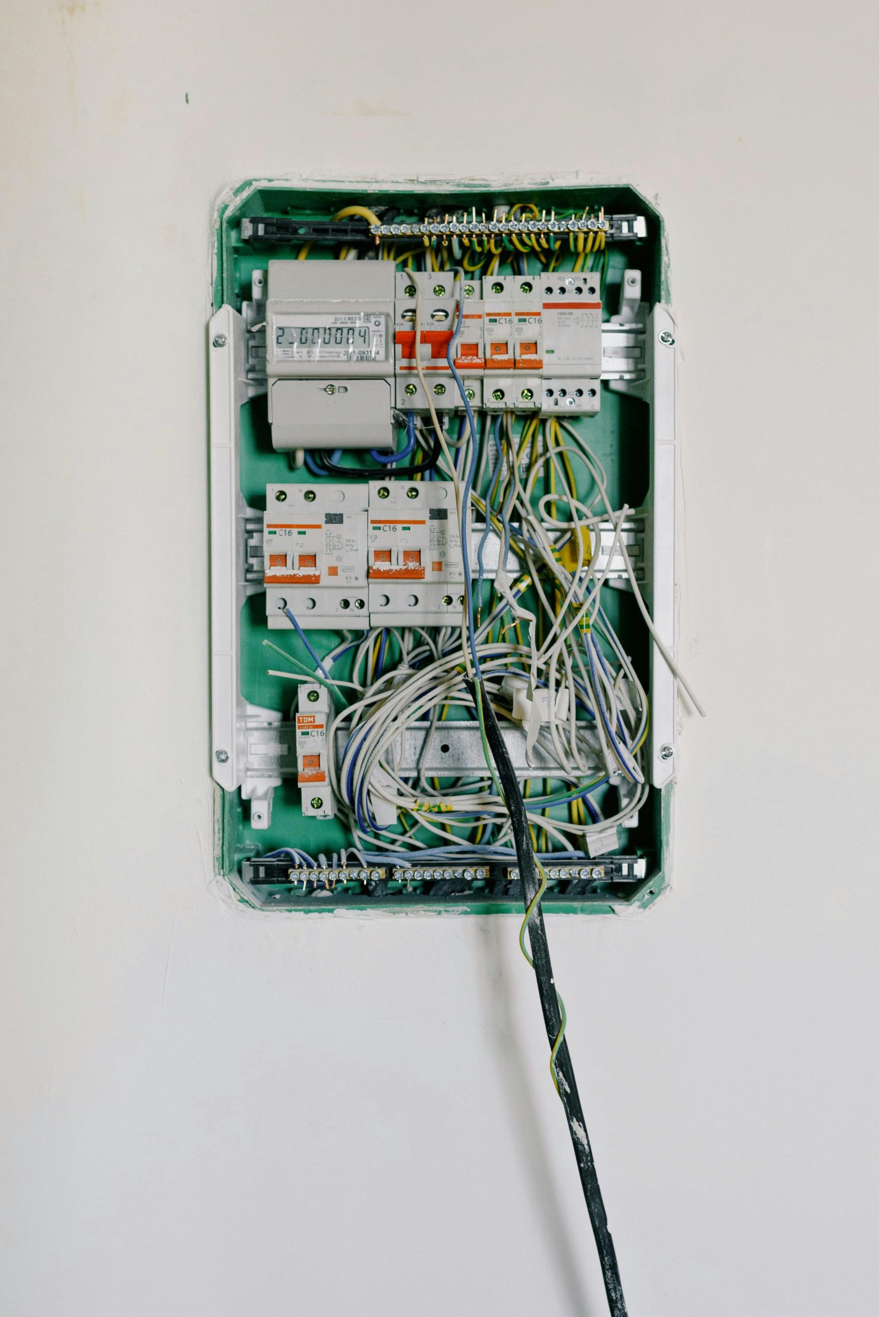 Détail d'un coffret électrique ouvert avec un câblage complexe et des disjoncteurs.