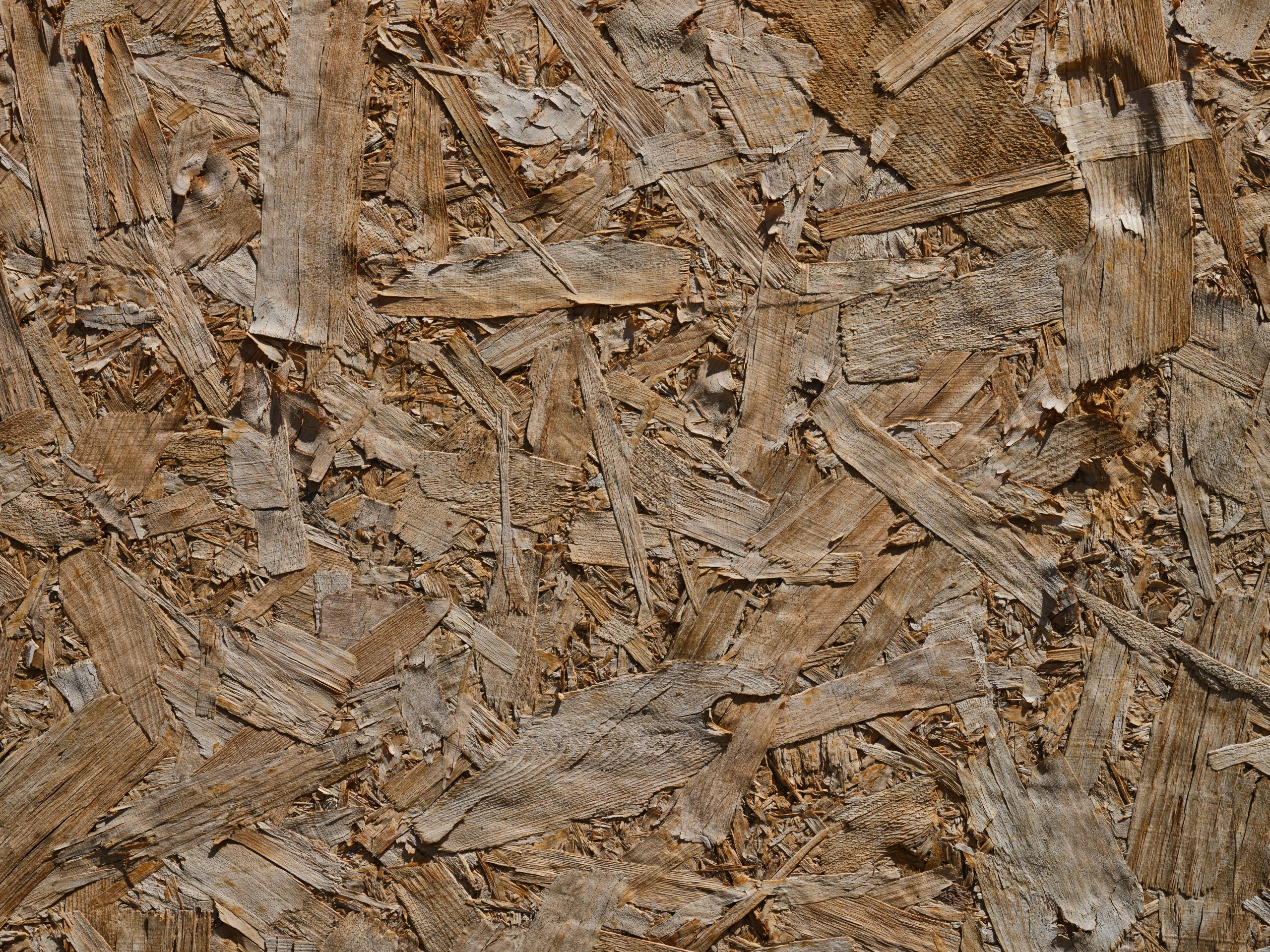 Détail en gros plan d'une surface de bois OSB texturée mettant en valeur les motifs et les teintes naturelles.