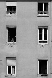 Vue en monochrome de fenêtres d'appartement avec une personne regardant dehors, design minimaliste.
